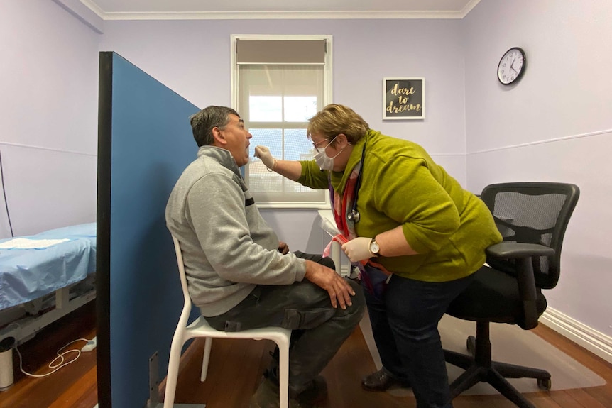 A female doctor takes an oral swab from a male patient.