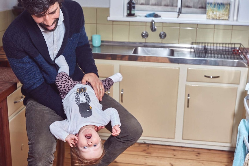 Brett Lee plays with his daughter, holding her upside-down, to depict the difficulties of parenthood.