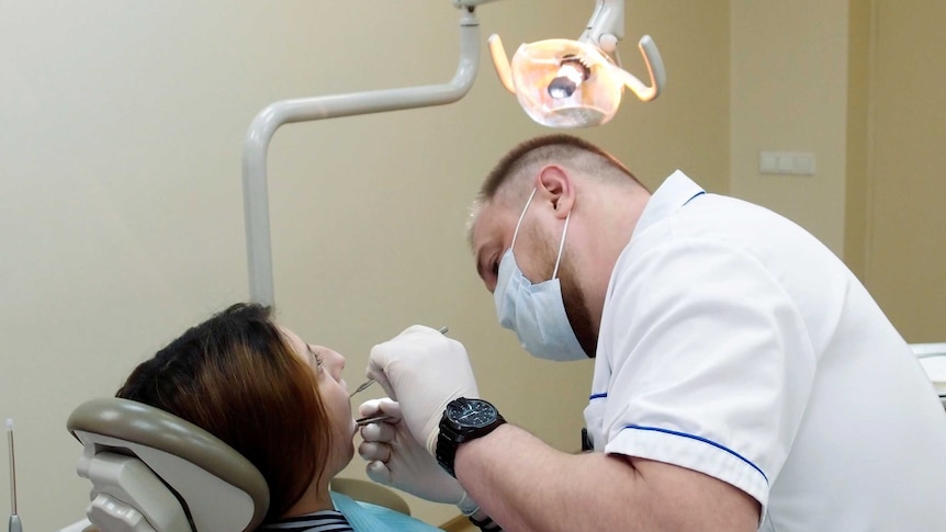 A dentist works on a patient.