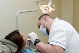 A dentist works on a patient.