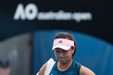Tennis player Peng Shuai drops her head as she caries her bag under an Australian Open sign.