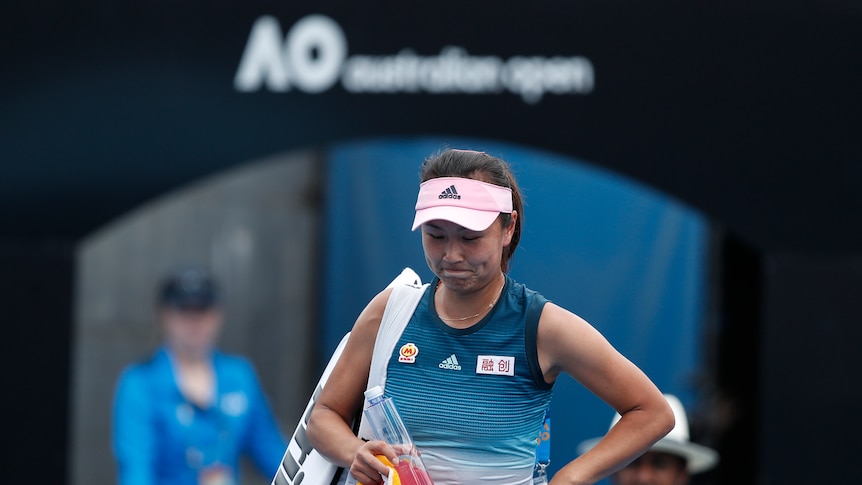 Tennis player Peng Shuai drops her head as she caries her bag under an Australian Open sign.