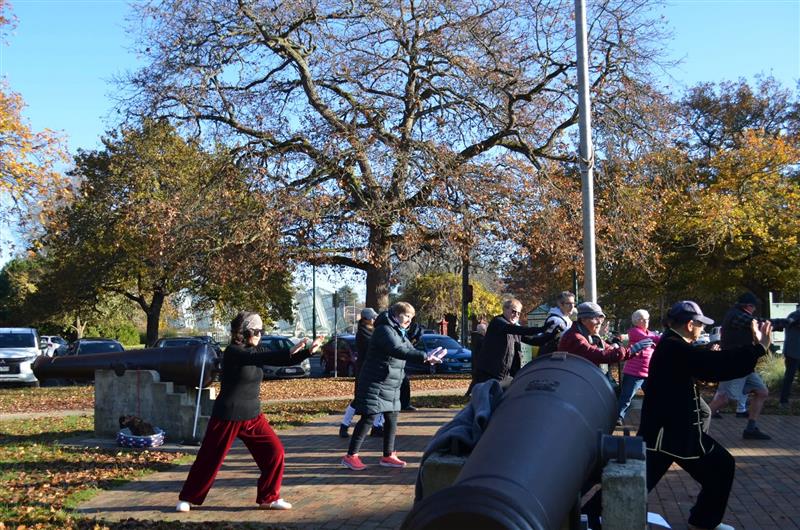 La gente practica Tai Chi en un parque. 