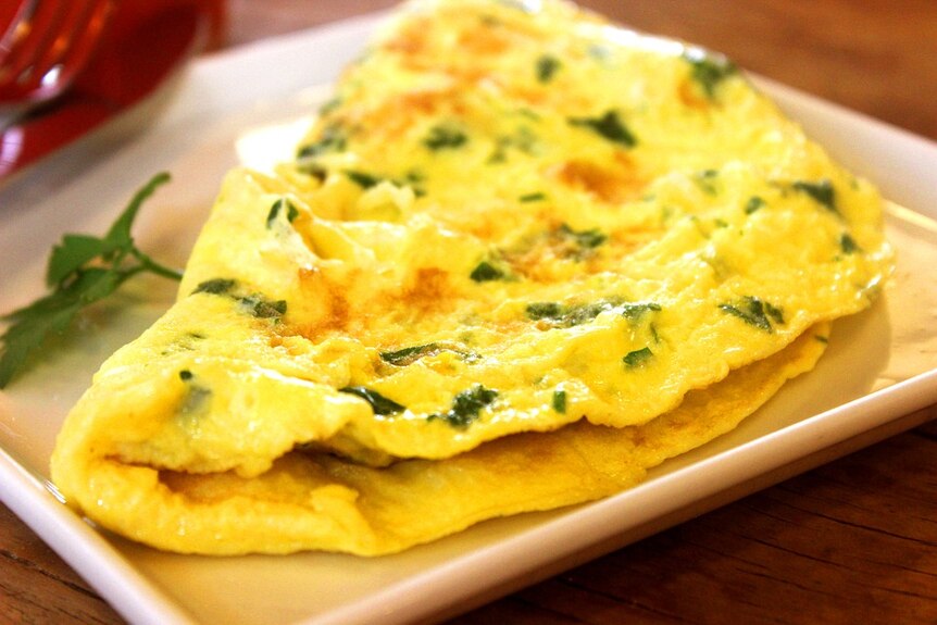 Omelette serve on a white plate with sprinkling of green garnish
