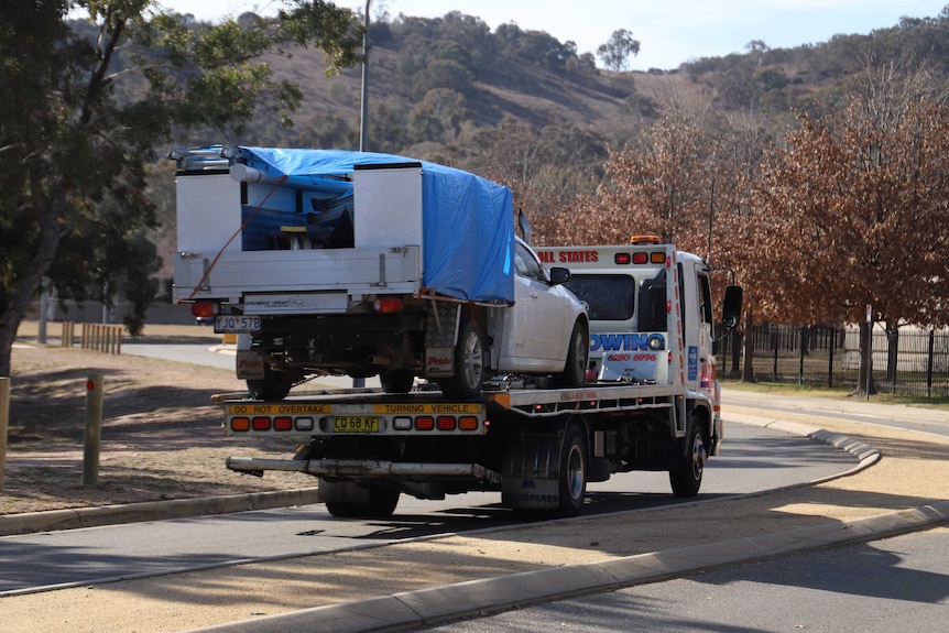 A ute with a blue tarpaulin on it is towed away from Canberra's St Clare of Assisi Primary School.