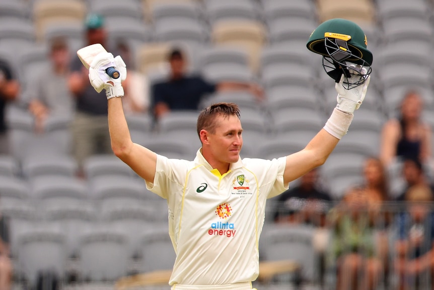 Marnus Labuschagne raises his bat and helmet in the air