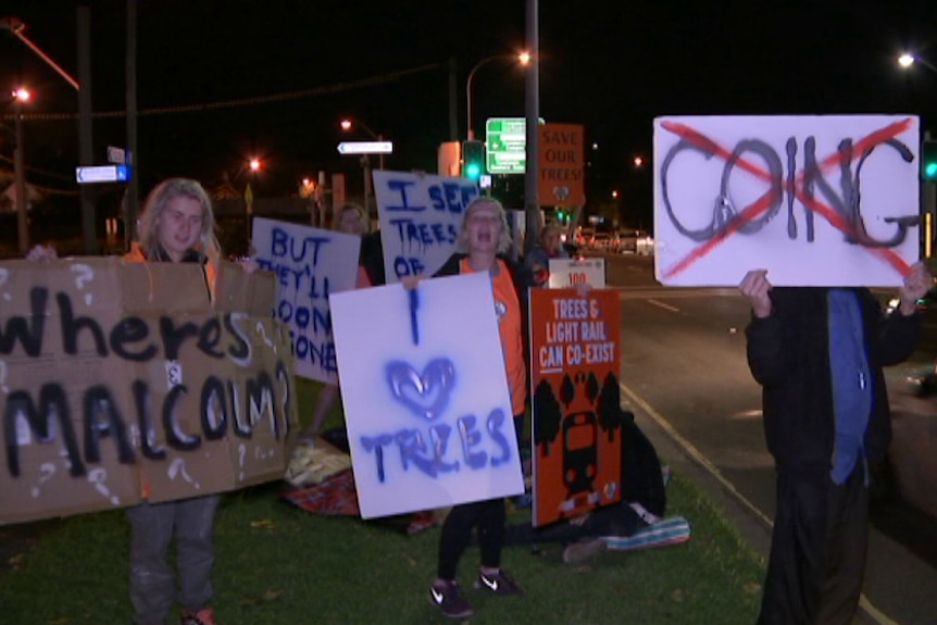 Protesters stand by the road holding signs