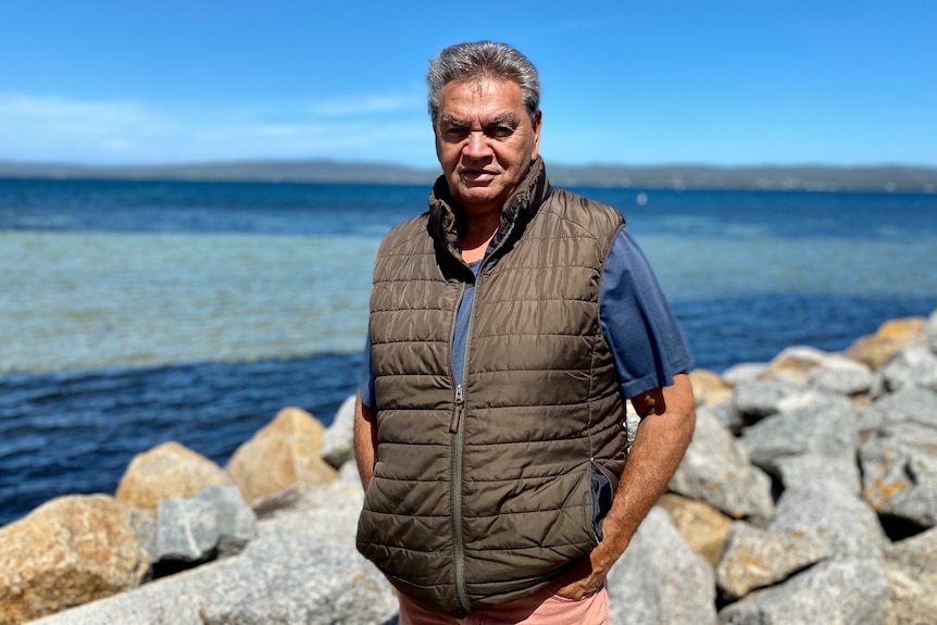 Aboriginal man stand in front of body of water