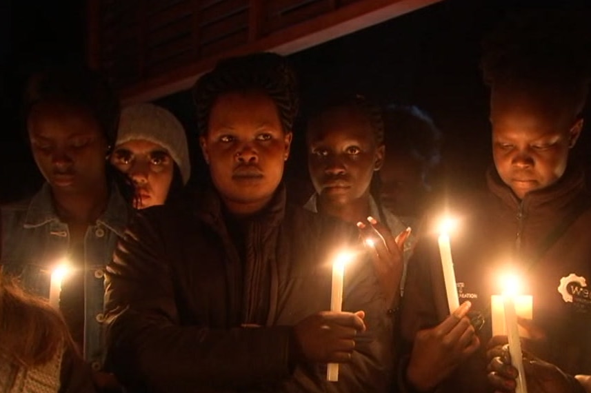 Women hold candles in honour of Abiol Atem Manyang at a vigil.