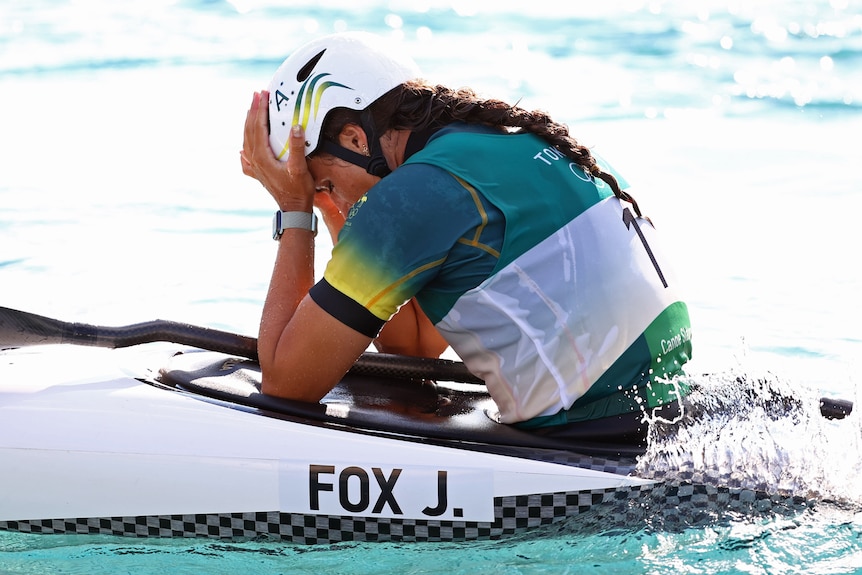 An Australian female kayaker in her canoe with her head in her hands.
