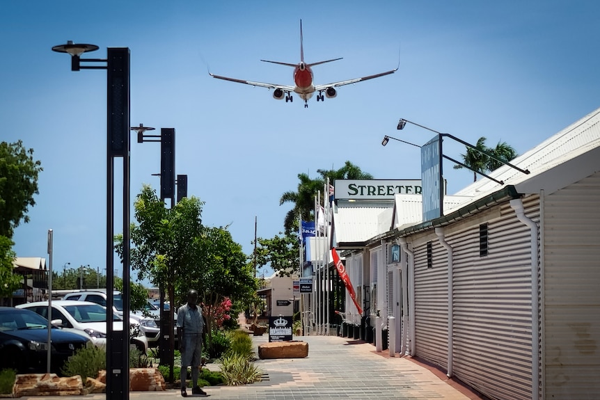 An airliner flies over a street.