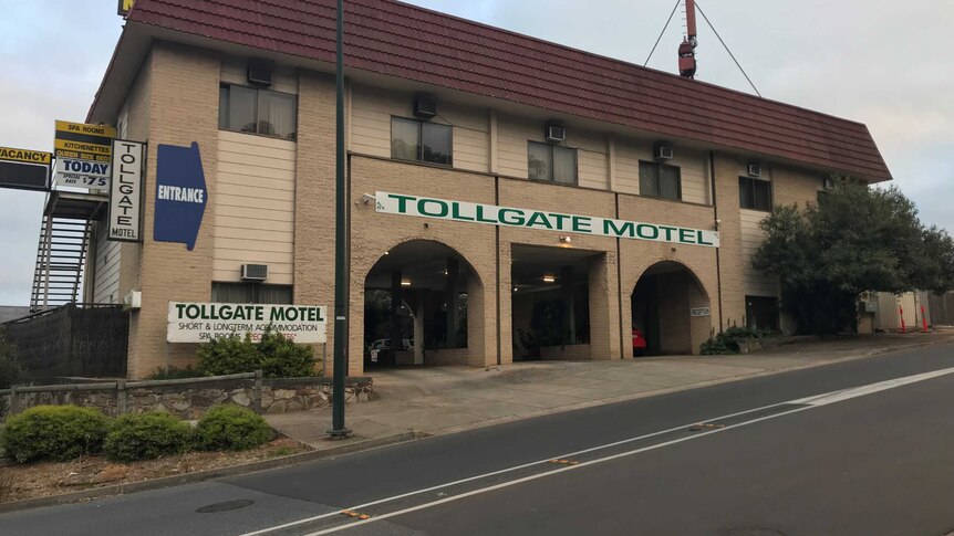 The photograph shows the exterior of a two-storey brick structure with a sign that reads Tollgate Motel.