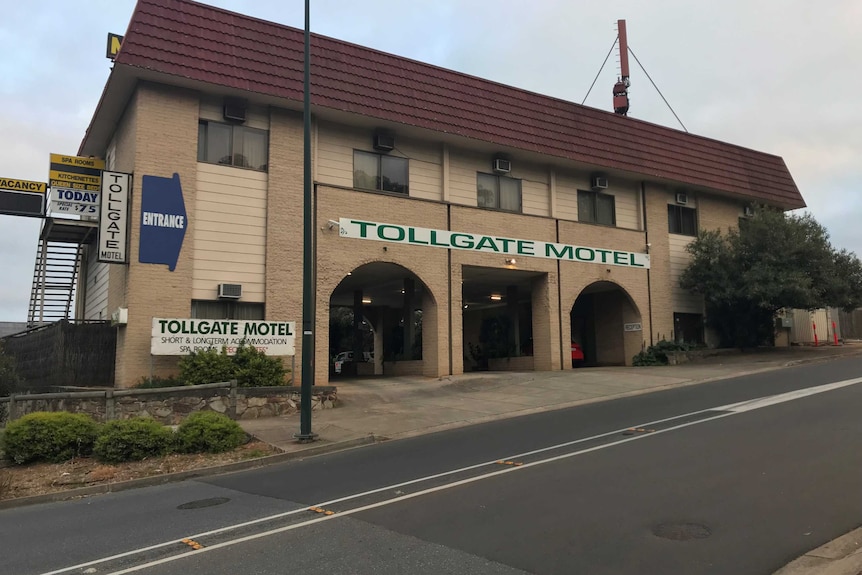 The photograph shows the exterior of a two-storey brick structure with a sign that reads Tollgate Motel.