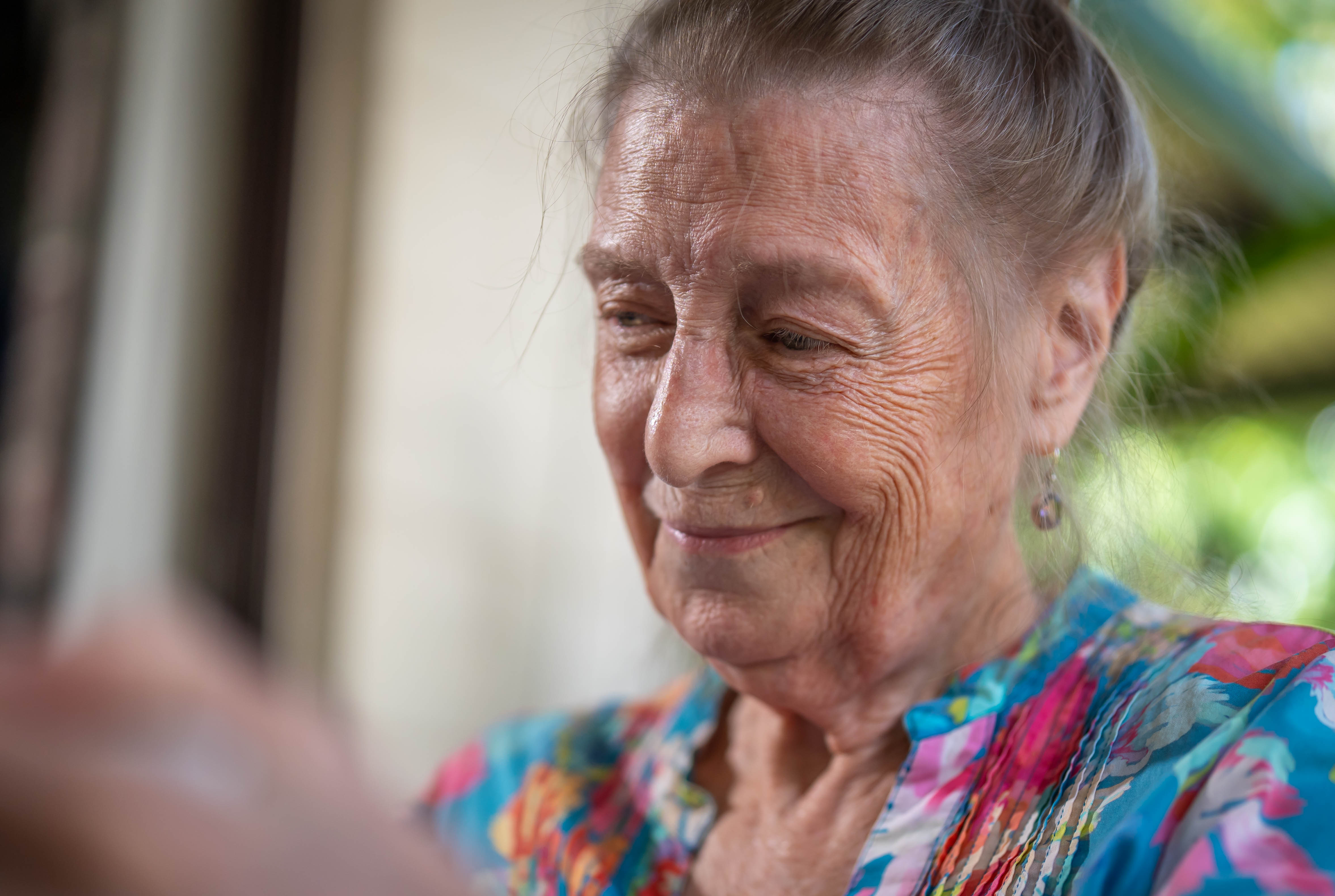A close up shot of Carolyn Marriott's face, as she smiles fondly while looking down at pictures out of frame.