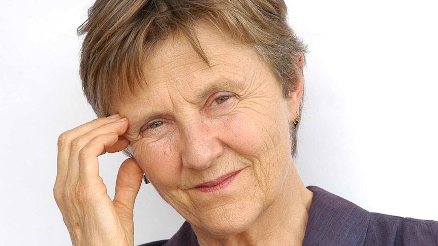 The writer, wearing a navy blouse, stares into the camera with a concentrated look on her face.