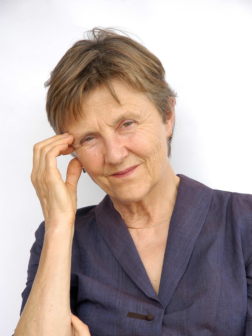 The writer, wearing a navy blouse, stares into the camera with a concentrated look on her face.