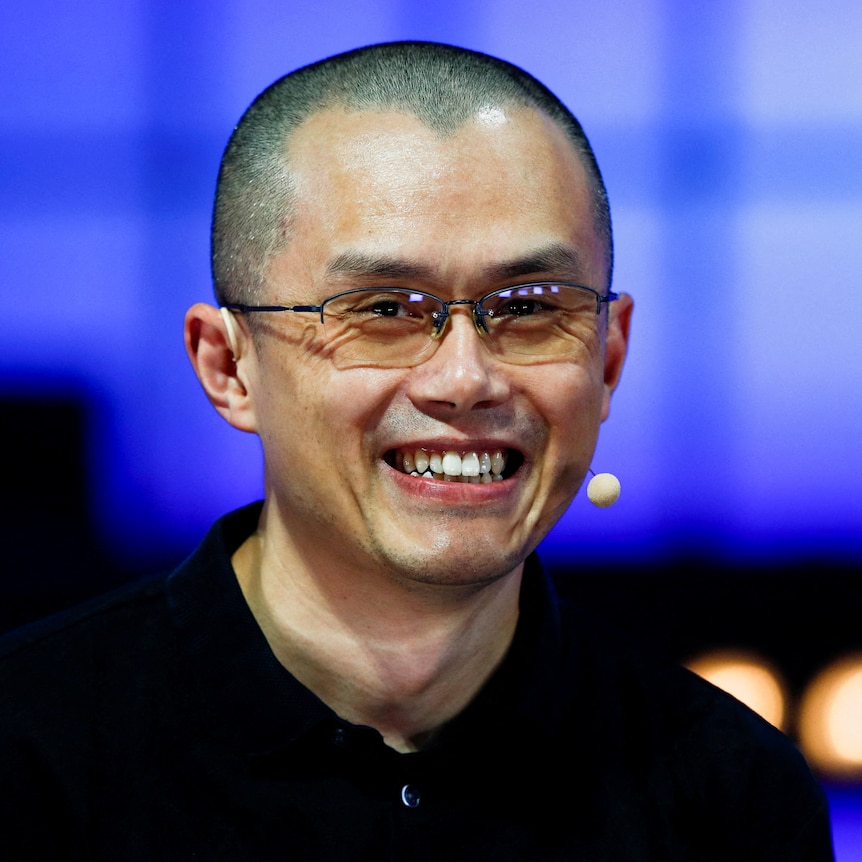 An Asian man with a buzzcut and glasses smiles 