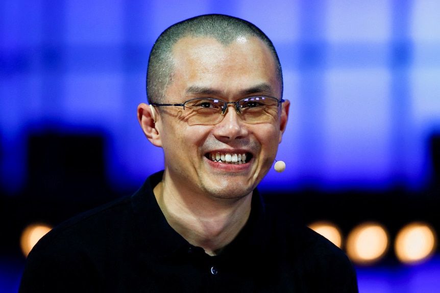 An Asian man with a buzzcut and glasses smiles 