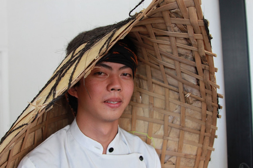 Indonesian musician Luqmanul 'Luk' Chakim demonstrates how the woven timber bundengan sits on your head to provide shade.