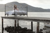 A young girl sits in a bed on a jetty