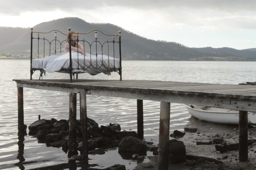 A young girl sits in a bed on a jetty