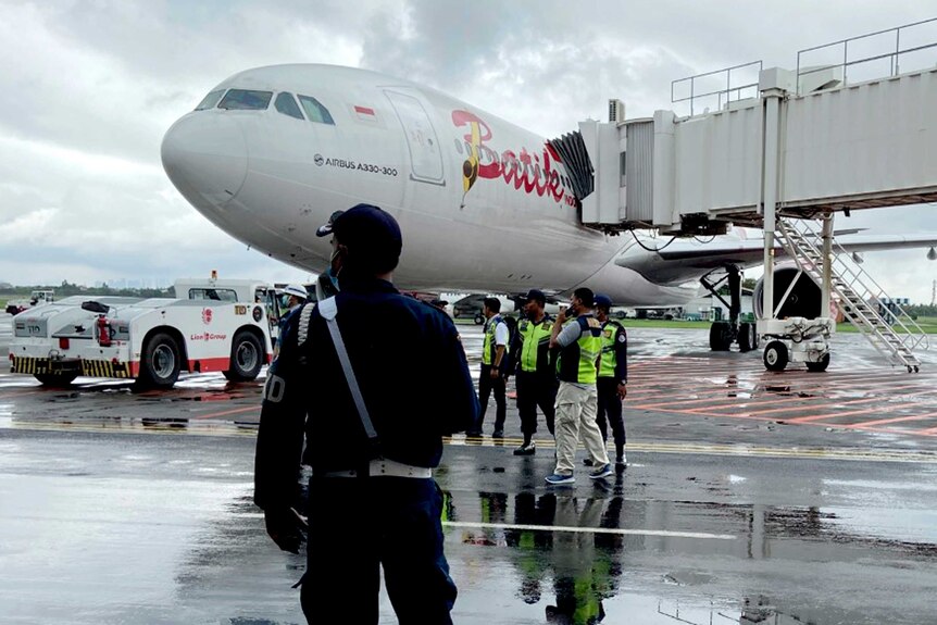 A security guard stands near a Batik Air jetliner parked on the tarmac before its departure to China.