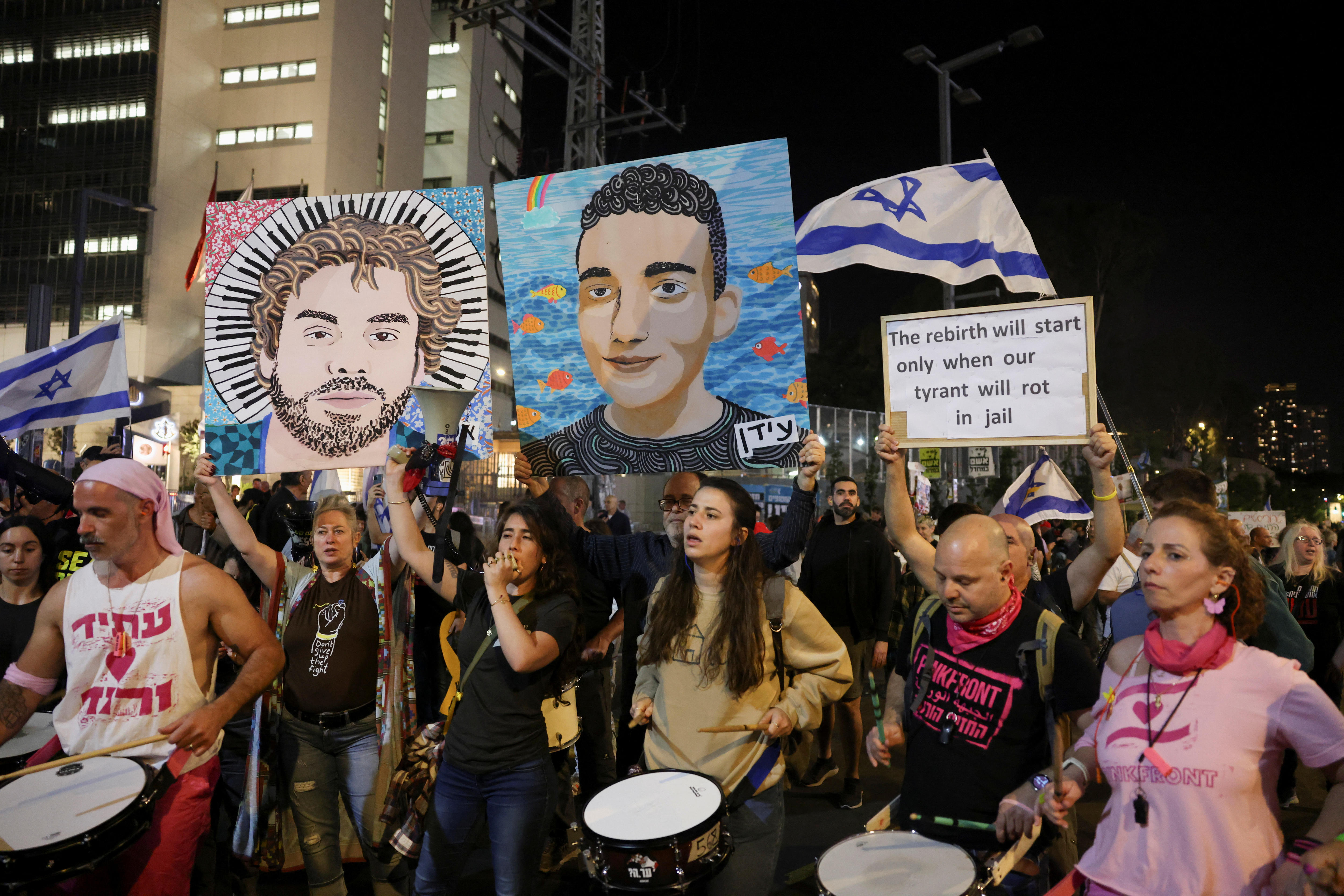 crowds of people protest in tel aviv holding signs of the hostages faces who were taken by Hamas