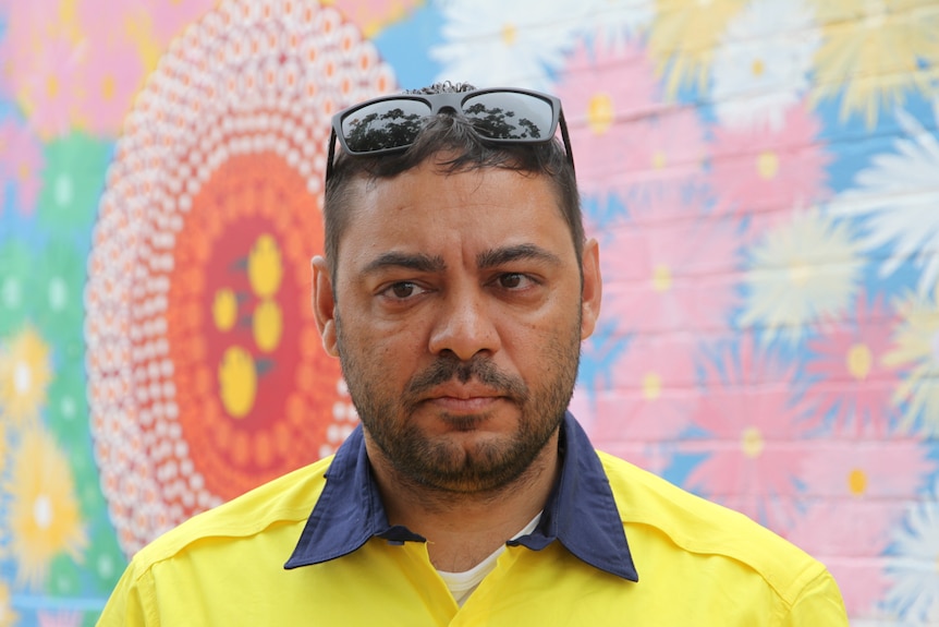 Wayne Abdullah stands in front of a painted mural
