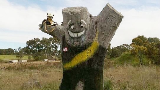 A tree stump has been decorated to look like a Richmond player who is holding a premiership cup