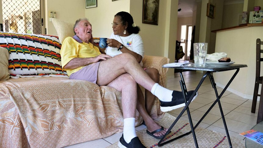 An elderly man and woman sitting on a couch.