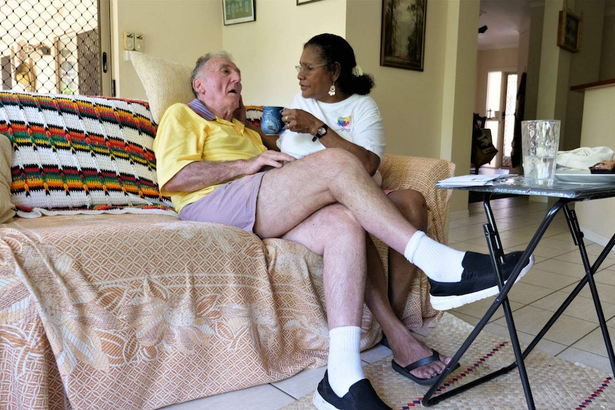 An elderly man and woman sitting on a couch.