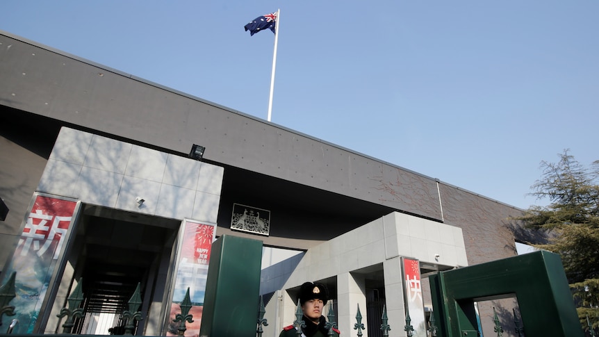 一名警察守在一座建筑物旁，建筑物上空飘扬着澳大利亚国旗