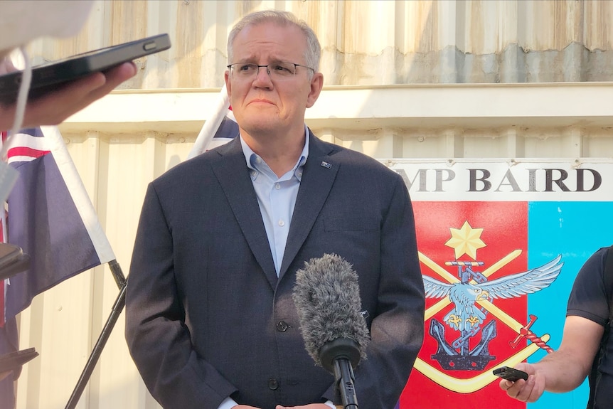 The Prime Minister stands without a tie at an airbase.