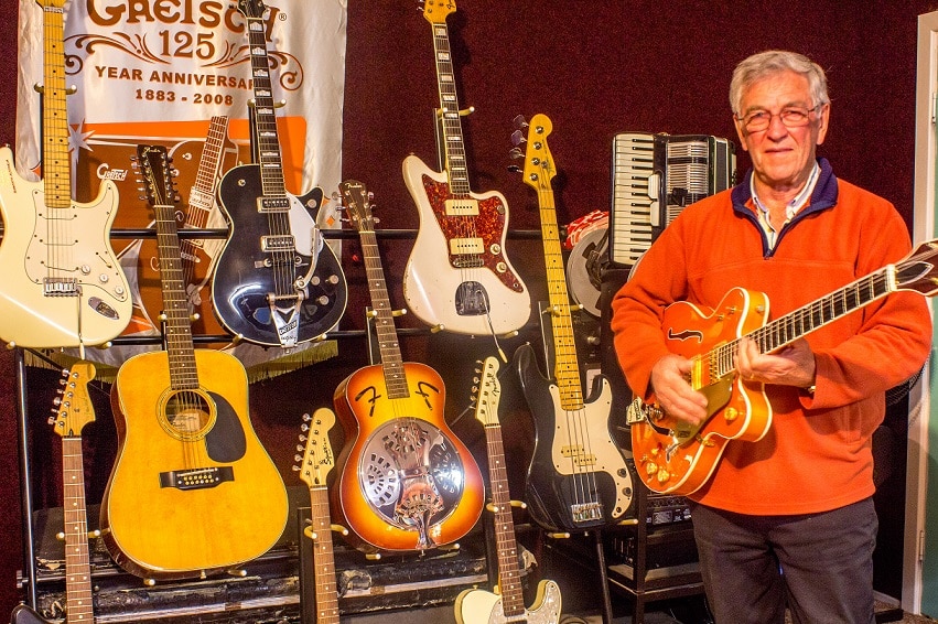 A man stands in front of guitars