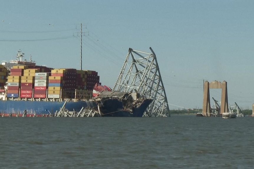 A cargo ship stuck in the wreckage of a bridge.