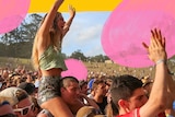 A young woman cheers from a mans shoulders in the crowd at Byron's falls festival.