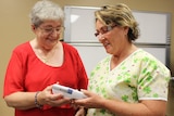 Catherine Iseppi hands over the handheld device to clinical nurse Elizabeth Ratcliffe