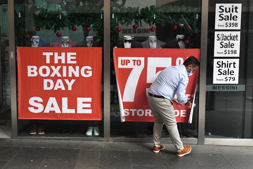 A man puts up posters on a shop window