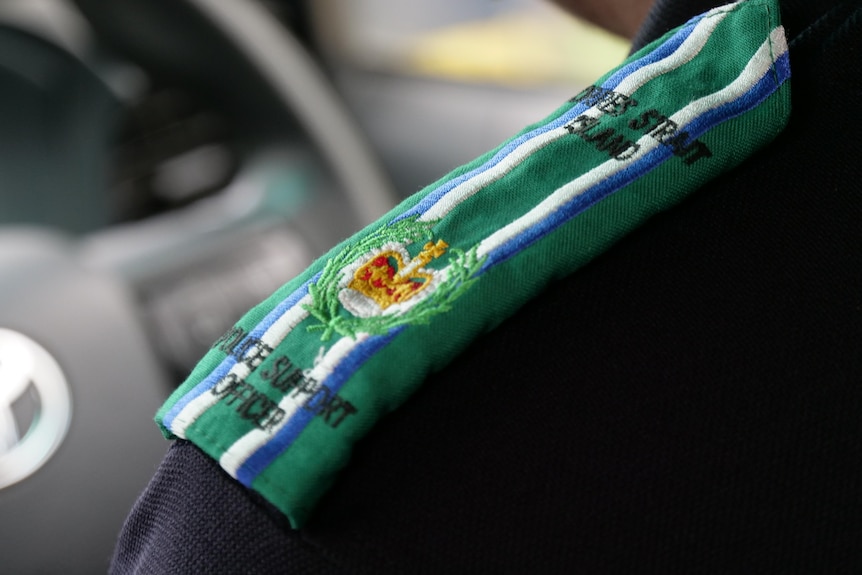 A close-up of a blue police uniform epaulets howing the colours of the Torres Strait flag and the words "Police Support Officer"