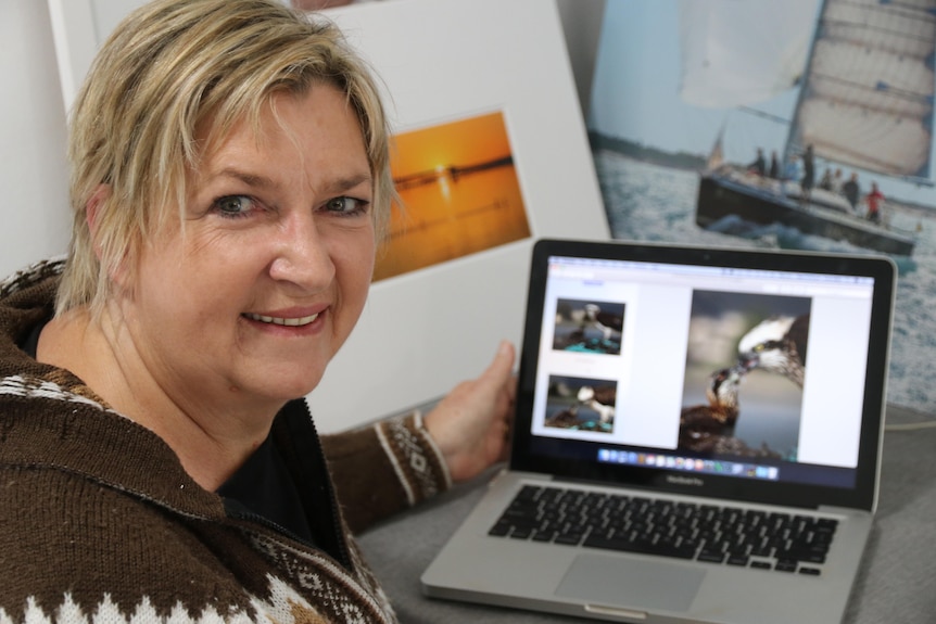 Woman turning head to look at camera in front of laptop with eagle feeding photo on display