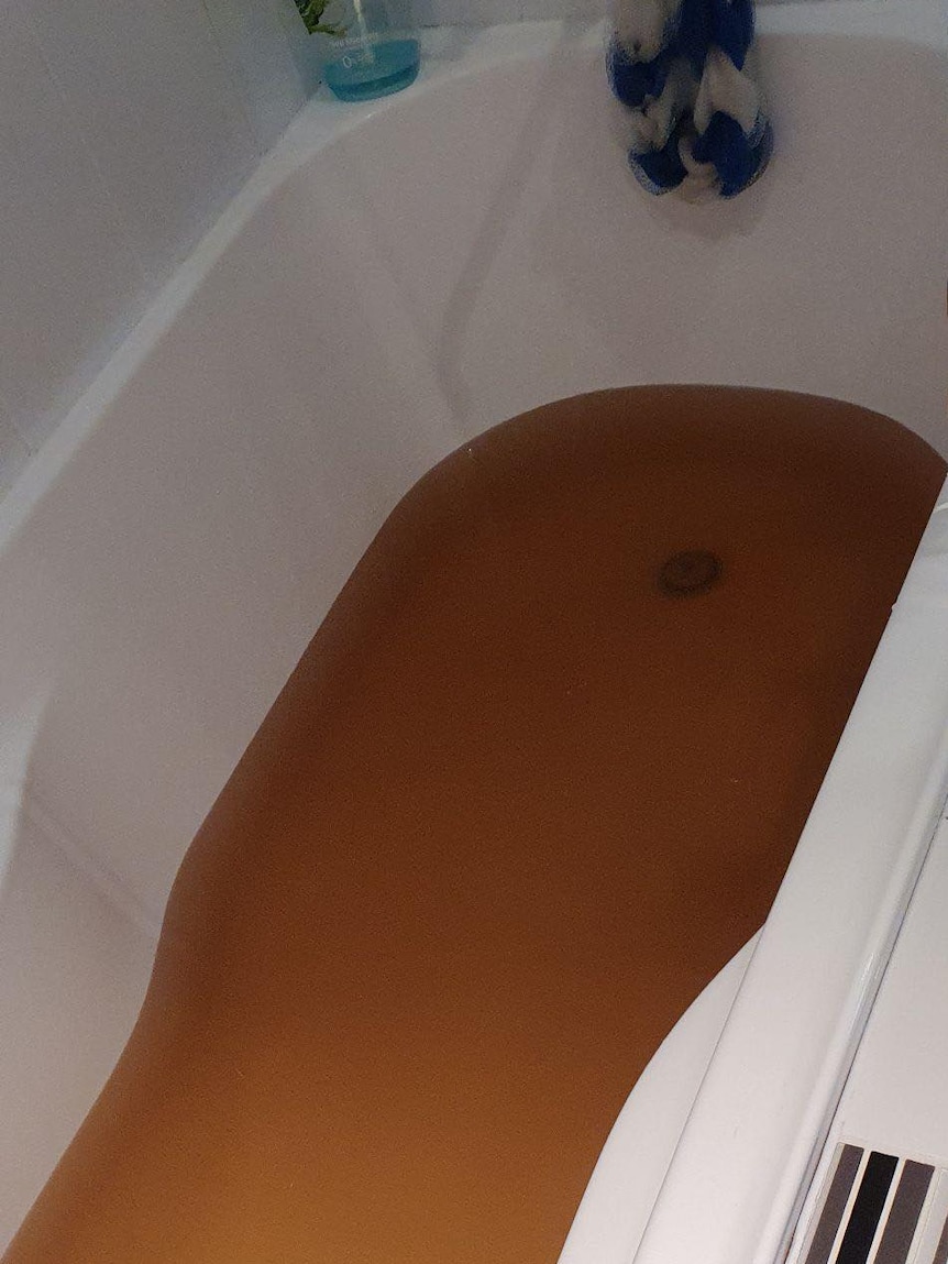 Brown, dirty water, that had just come out of a tap, in a bath tub.