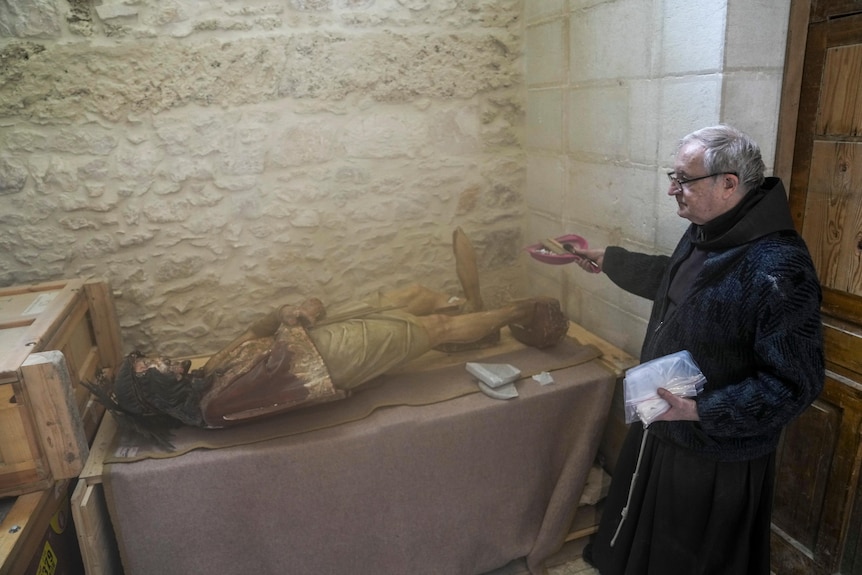 A priest stands by a damaged statue of Jesus in the Church of the Flagellation in Jerusalem's Old City.