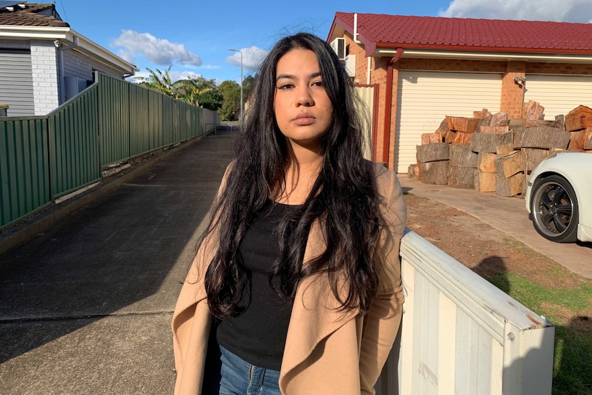 A young woman standing outside on a suburban street.