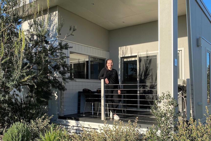 Emme Malone stands on the verandah of a holiday cabin.