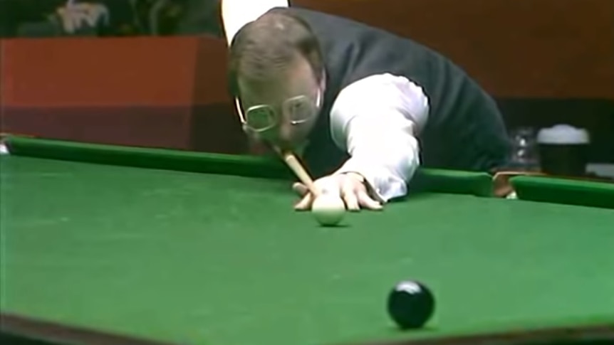 Dennis Taylor holds a snooker cue and lines up the black to a corner pocket