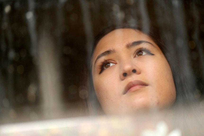 Anna looks through a window.