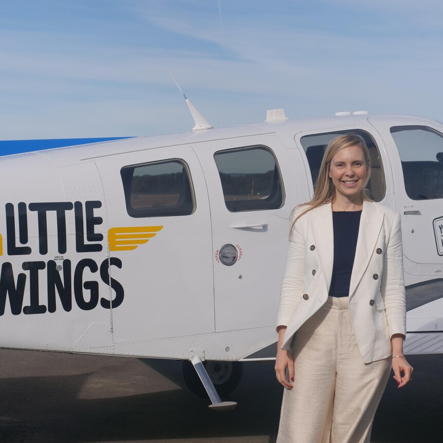 Clare Pearson in front of a small plane with a Little Wings sticker on it.