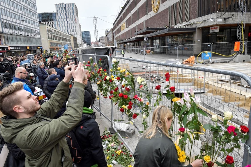 People gather near the crime scene, near Ahlens department store