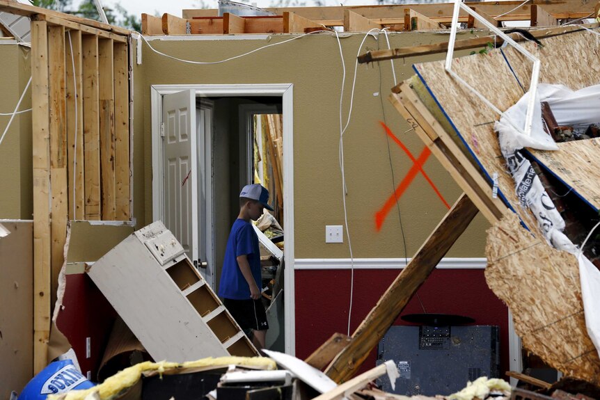 A boy walks through a house wrecked by a tornado in Van, Texas.