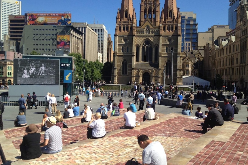 People gathered in front of a screen in Federation Square.